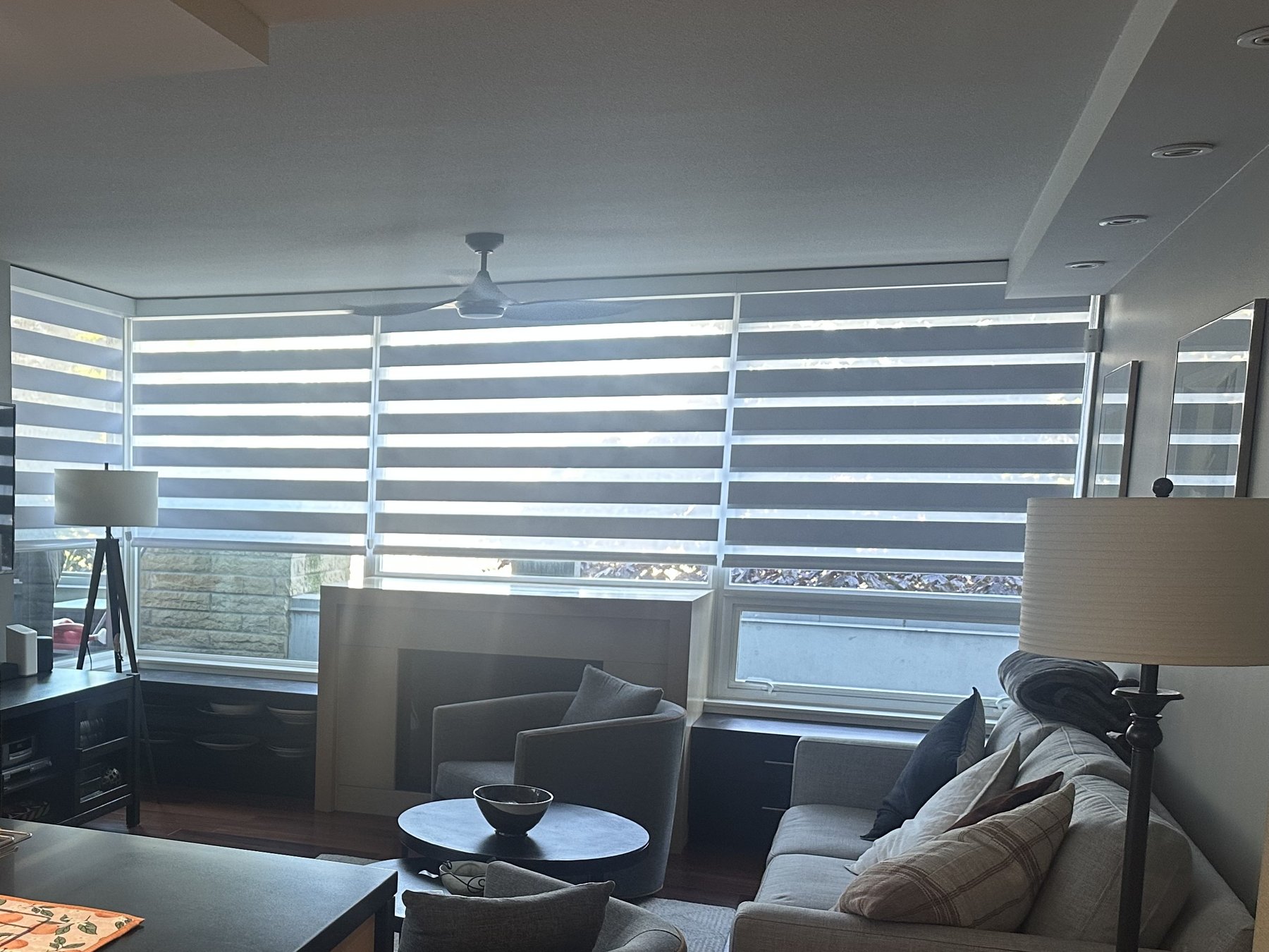 Zebra shades wrapping a corner window living room